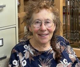 photograph of a woman wearing thin framed glasses and a flower top.